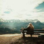pexels-photo-592941-592941 Woman enjoys a peaceful view of snow-capped mountains from a bench, capturing the essence of nature's serenity.